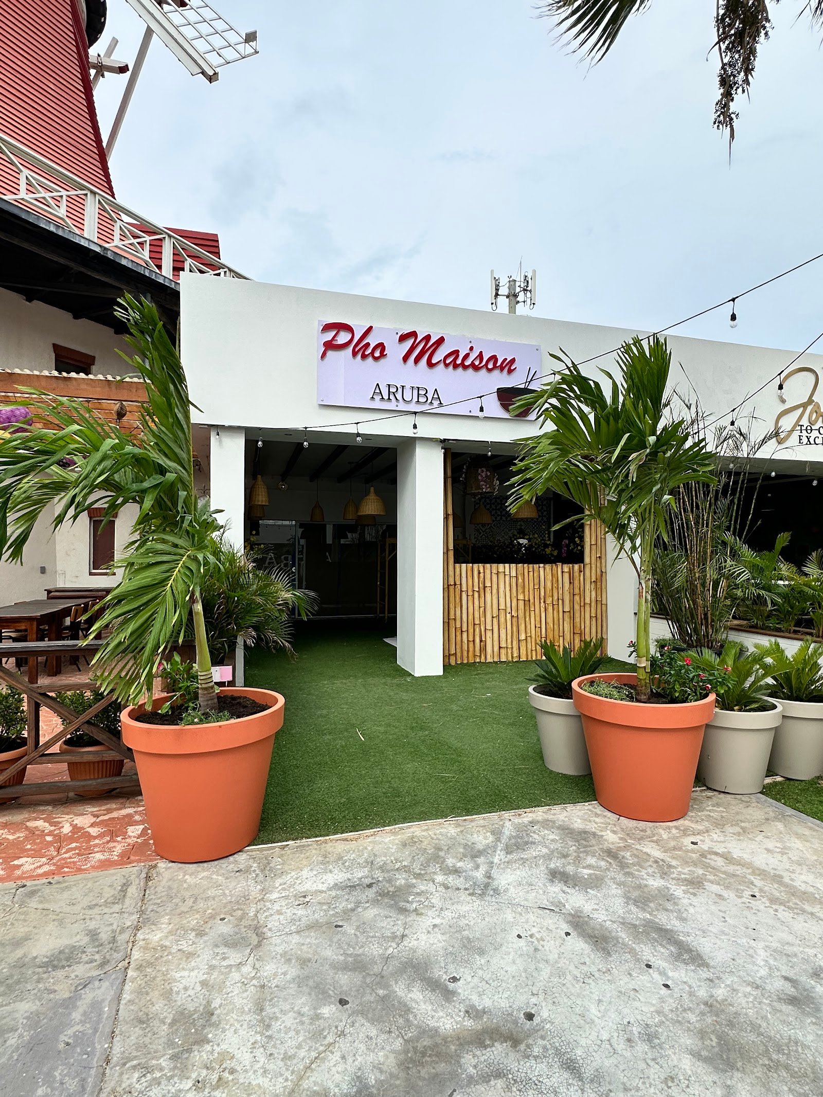 Pho Maison Aruba storefront on L.G. Smith Boulevard, with palms and turf terrace