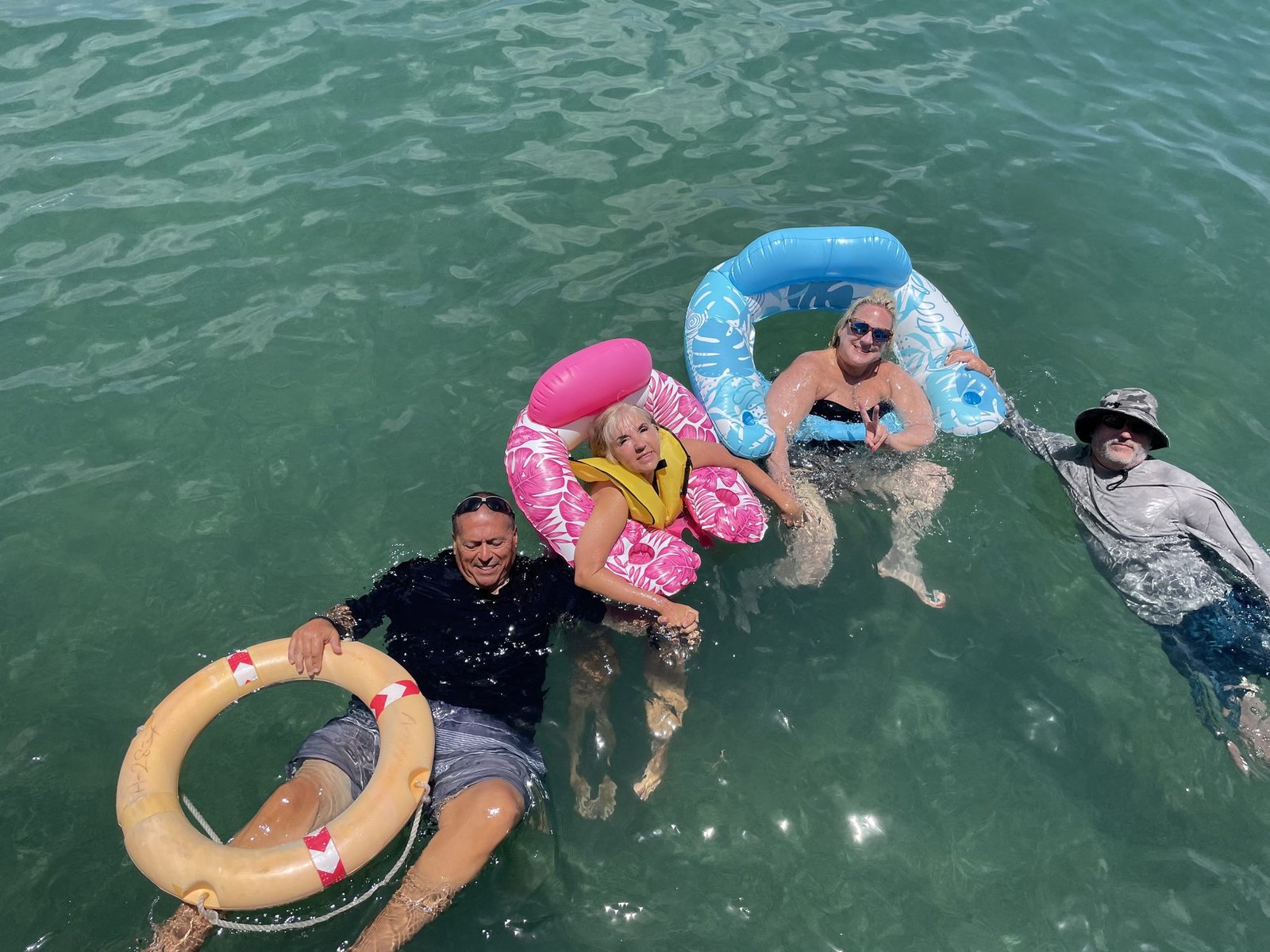 Guests floating beside the boat on an Aruba pontoon boat charter at Mangel Halto