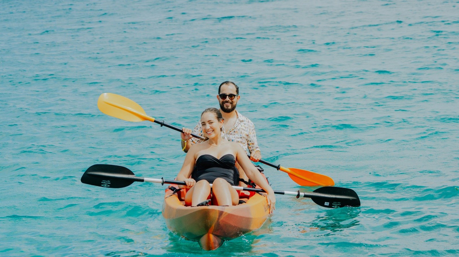 Couple kayaking in clear water on a private island day in Aruba