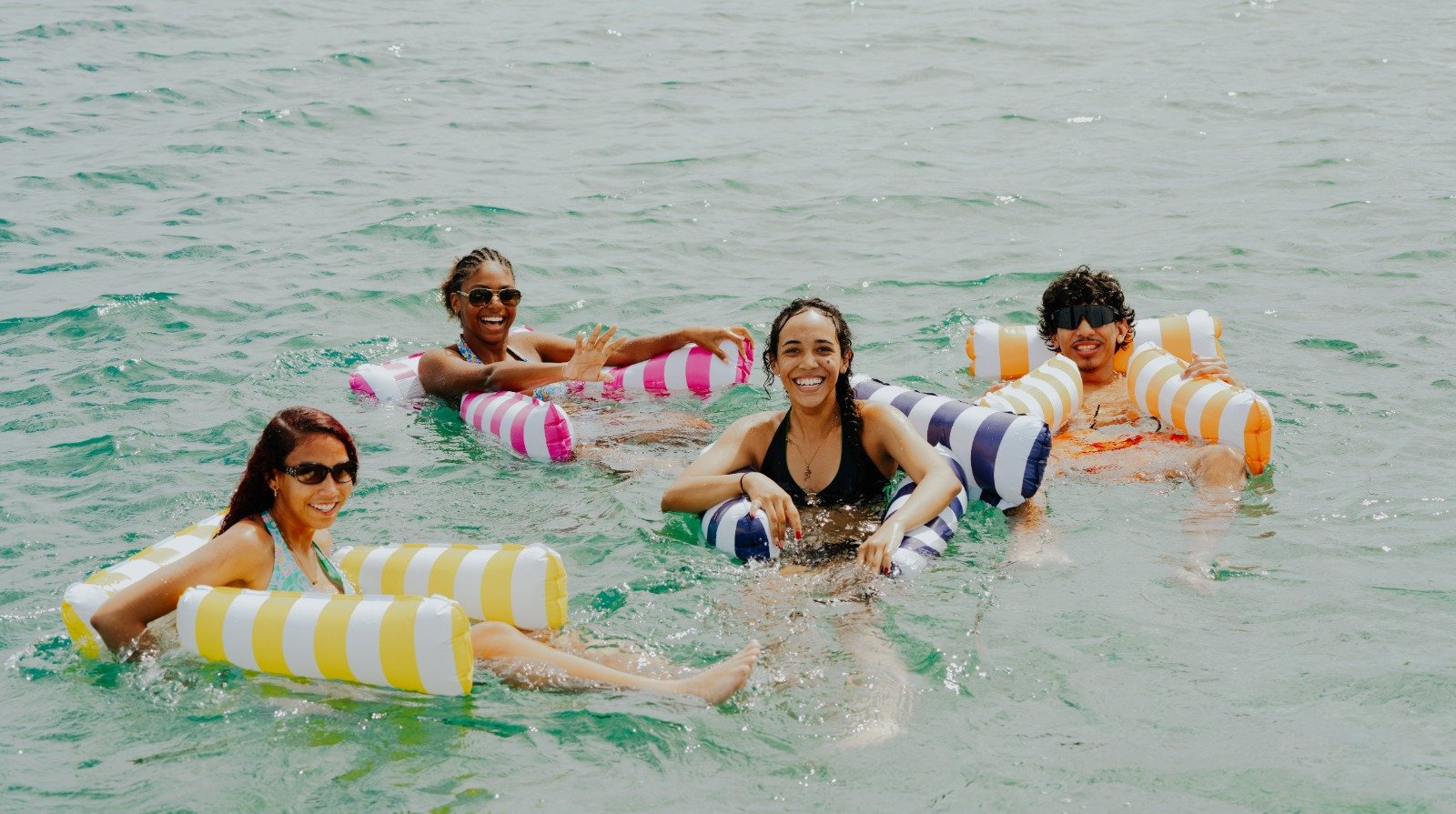 Friends floating on inflatables off a private island in Aruba
