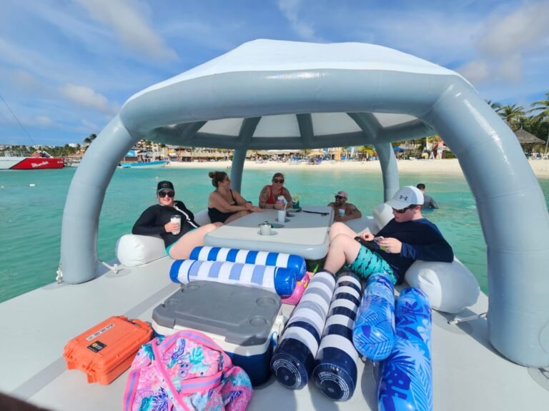 Friends around the table under the Bonanza Lounge canopy with a cooler, floats and a dry case