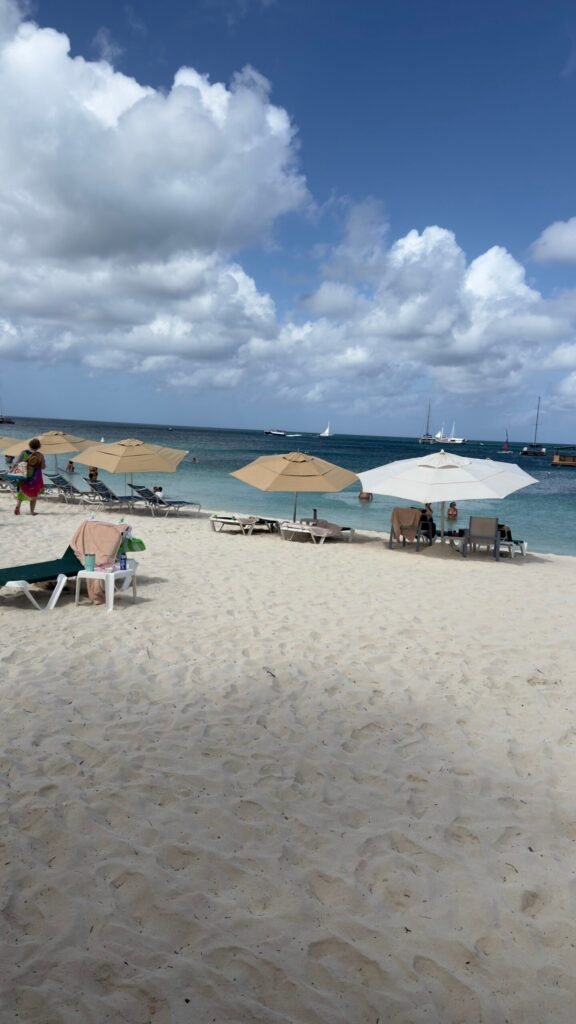 Beach umbrella and two chairs set up on the sand in Aruba, ready for guests